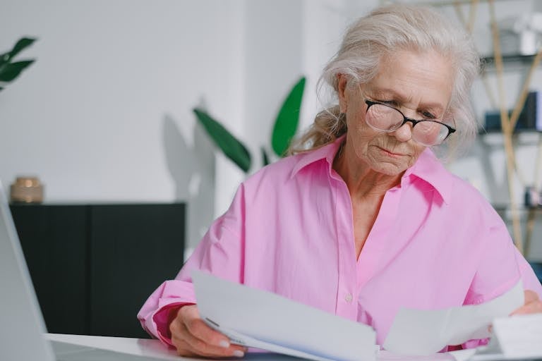 Femme senior consultant ses documents de pension de reversion après le décès de son conjoint